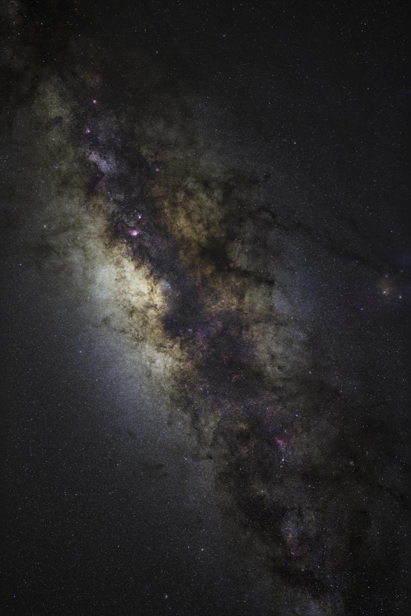 Samanyolu'nun yıldızlı bir görüntüsü gece gökyüzünde uzanarak görüntüyü sol üst köşeden çaprazlamasına doldurur